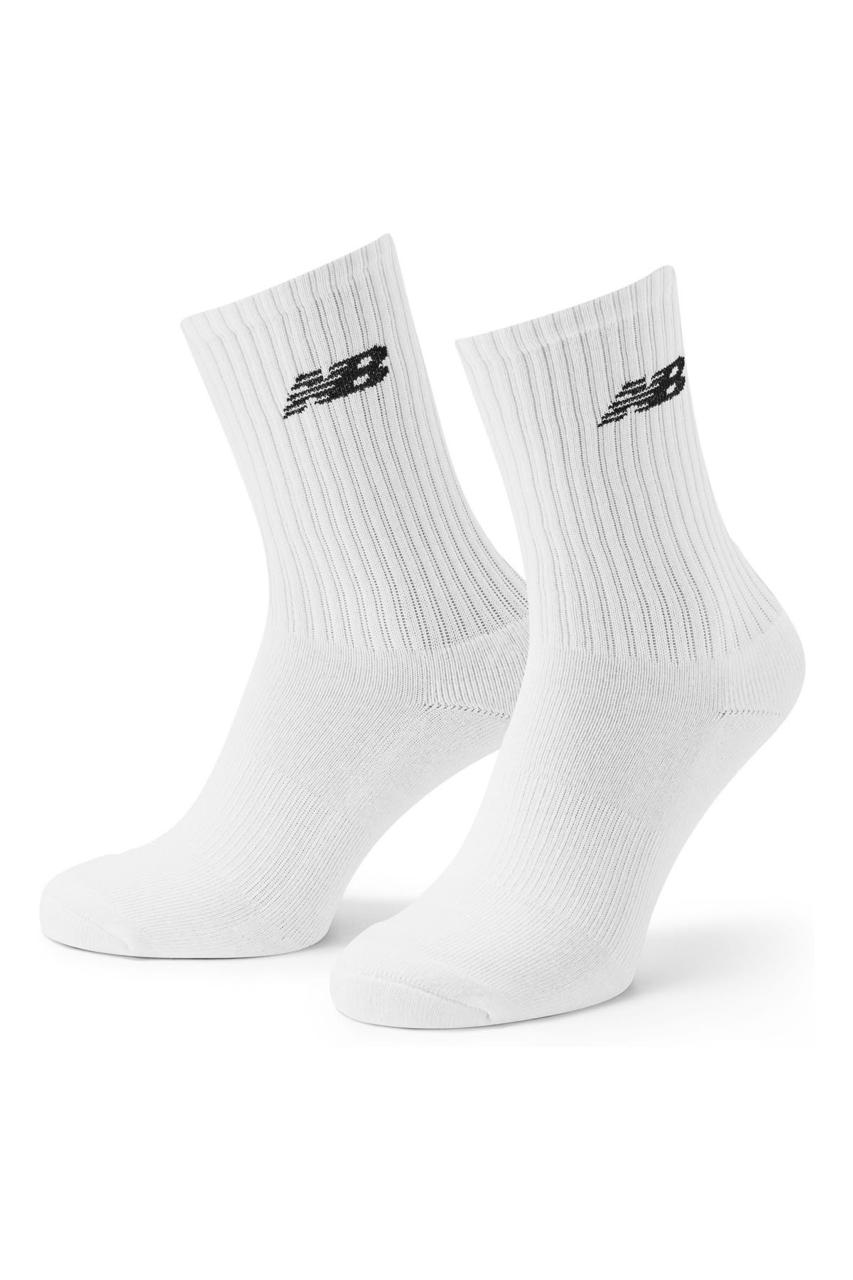 Pair of white New Balance crew socks with black logo on ribbed cuffs, isolated on white background.