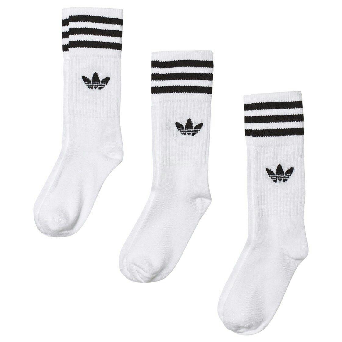 Three pairs of white Adidas crew socks with black stripes and trefoil logo on a plain background