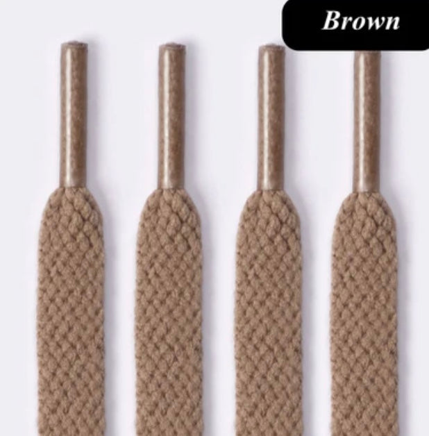 Four brown flat braided shoe laces with plastic tips on a light background
